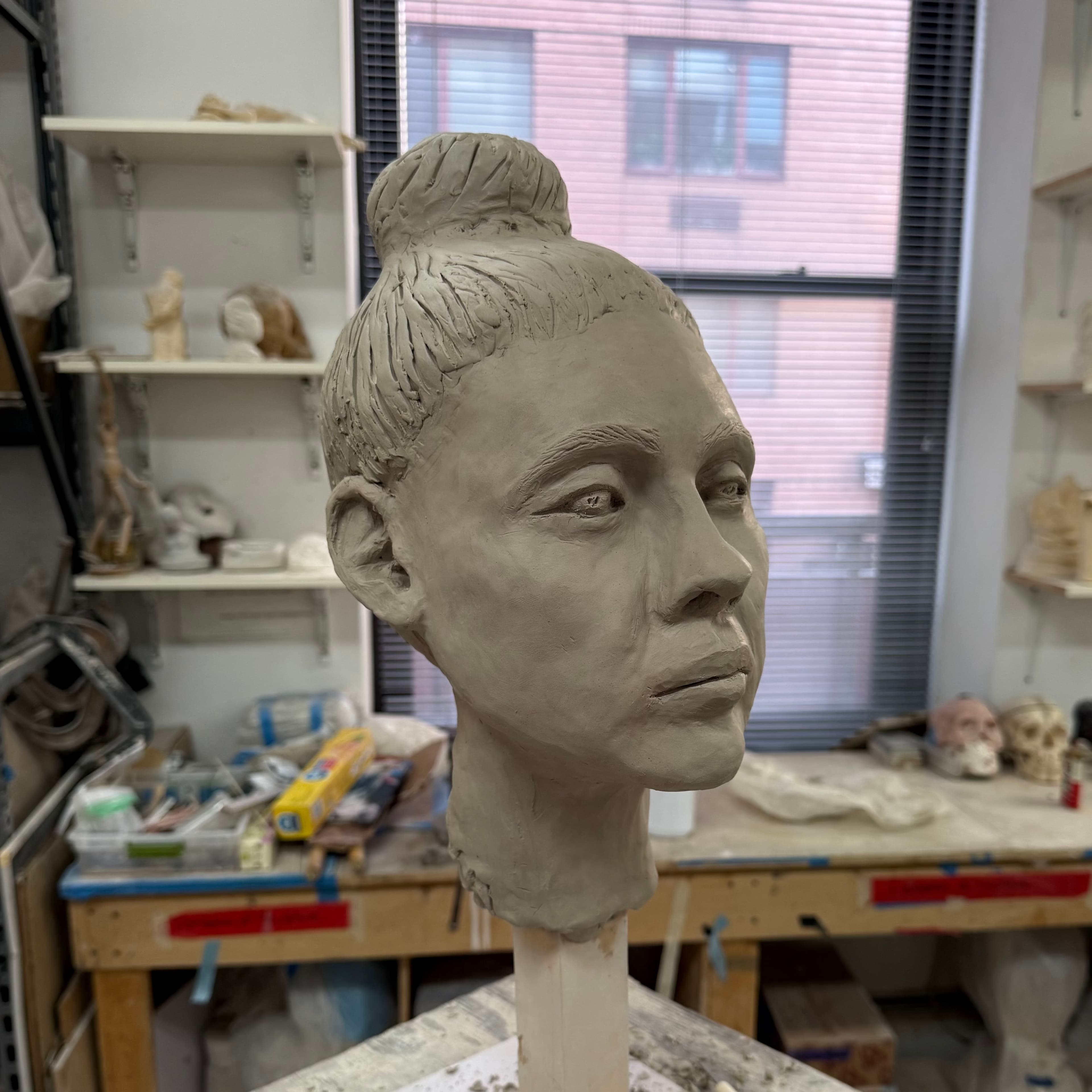 Three-quarter view of the clay portrait in the sculpture studio